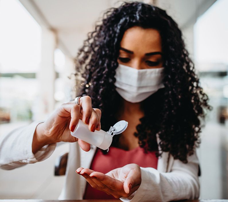 Woman wearing face mask pouring medication into hand