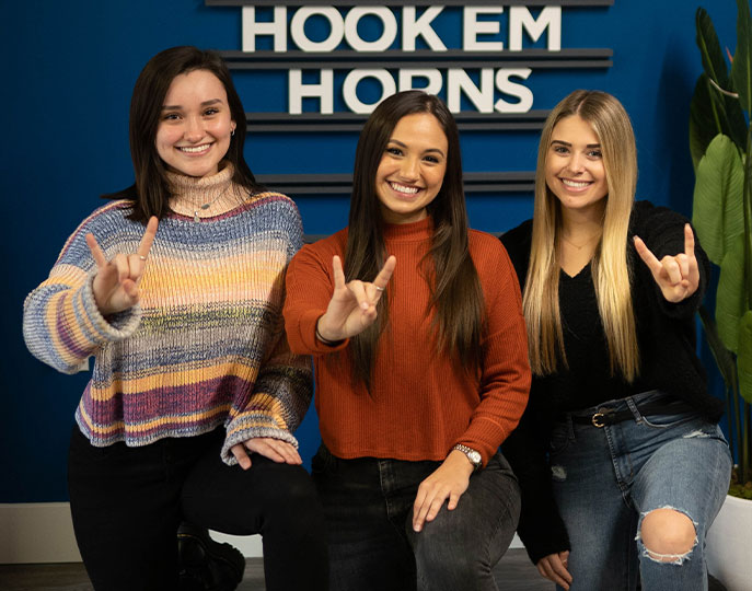 Three girls holding up hand signs